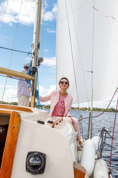 sailor man in a cap with a girl on a boat under sail against the