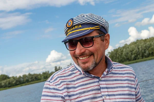 sailor man in a cap on a boat under sail against the sky and wat