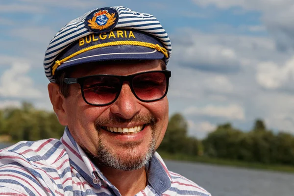 sailor man in a cap on a boat under sail against the sky and wat