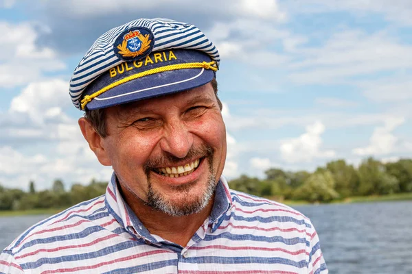 sailor man in a cap on a boat under sail against the sky and wat