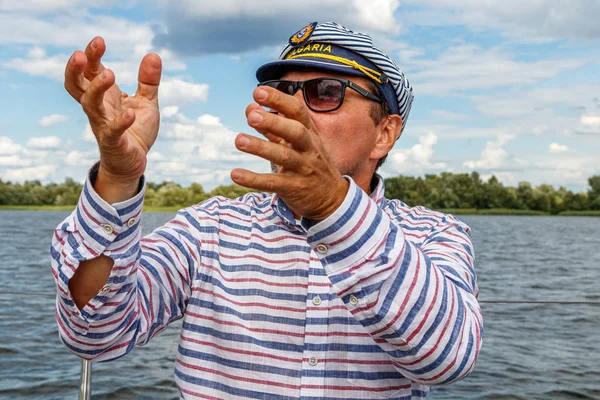 sailor man in a cap on a boat under sail against the sky and wat