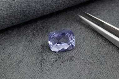 Gri bir kumaşa cımbız yapıştırılmış makro mineral taş ametist.