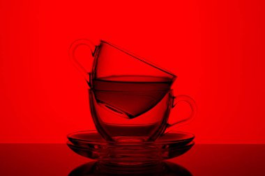 Kırmızı zemin üzerinde çay olan iki güzel kupa.