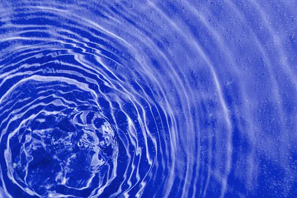 drops on water with circles on a blue background close up