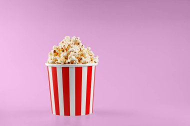 Pembe arka planda klasik kırmızı çizgili patlamış mısır karton bardak.