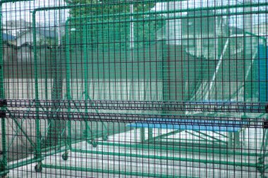 Beyzbol sahasını çevreleyen mavi mozaik desenli metal bir ağ.