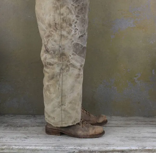 legs of a man in old pants and old shoes
