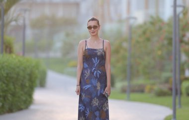 Uzun, ince esmer kadın portresi. Tatil köyünde, koyu renkli, uzun elbiseli.