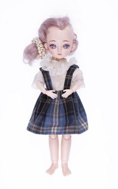 Pembe saçlı, beyaz arka planda soyutlanmış elbisesi olan plastik kız bebeği.