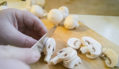 Yemek pişirmek için hazırlanan ve ahşap tahta üzerinde keskin bıçakla dilimlenmiş mantar