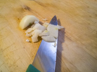 Soğan yemek pişirmek için hazırlanan ve küçük küpler halinde bir ahşap tahta üzerinde keskin bir bıçak ile kesmek.