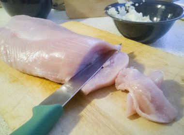 Yemek pişirmek için hazırlanan ve ahşap tahta üzerinde keskin bıçakla dilimlenmiş hindi eti