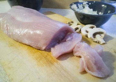 Yemek pişirmek için hazırlanan ve ahşap tahta üzerinde keskin bıçakla dilimlenmiş hindi eti