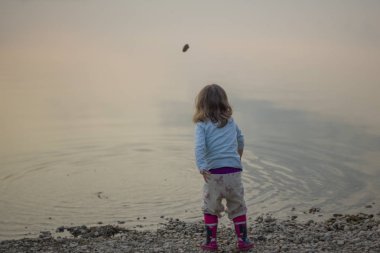 Genç kızın çakıl denizde atma arkadan görünüş