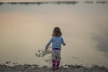 Genç kızın çakıl denizde atma arkadan görünüş