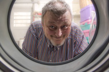 Adam çamaşır makinesine bakıyor.