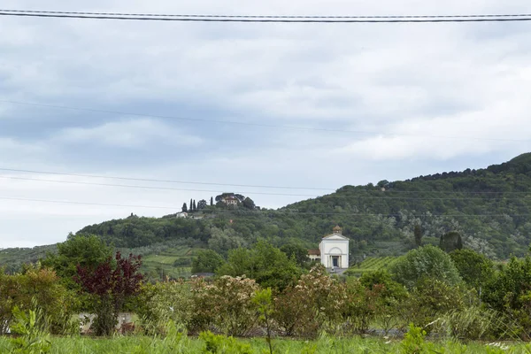 Single house in a hilly area in the Italian region Tuscany in front of a cloudy sky