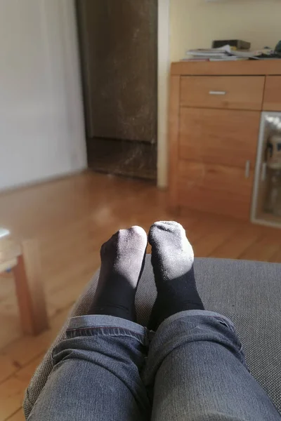 Feet with steaming socks on a stool in a room