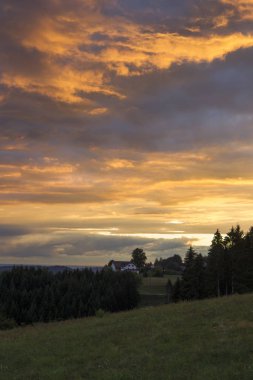 Evin önünde bir dramatik akşam gökyüzü günbatımı için ağaçların arasındaki kara orman