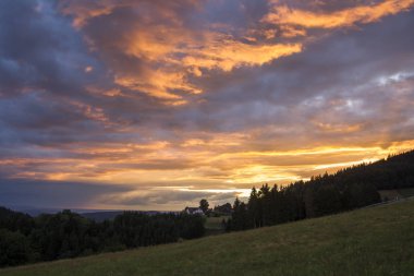 Evin önünde bir dramatik akşam gökyüzü günbatımı için ağaçların arasındaki kara orman