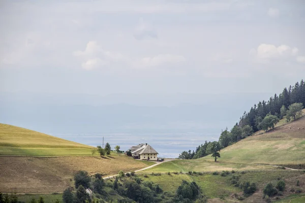 Lonely Black Forest farm between two mountains in front of a cloudy sky with a view of the Rhine plain