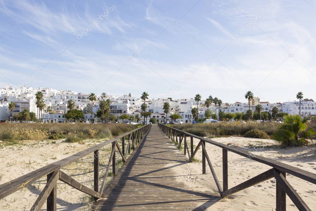 Wooden boardwalk and white city of Conil de la Frontera in Andalusia, Spain