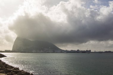 Cebelitarık üzerinde deniz üzerinde Algeciras limandan görünümü ve kara bulutlar arkasında kayalar