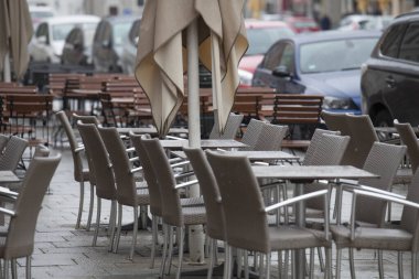 Yağmurda bir sokak kafesinin masa ve sandalyeleri