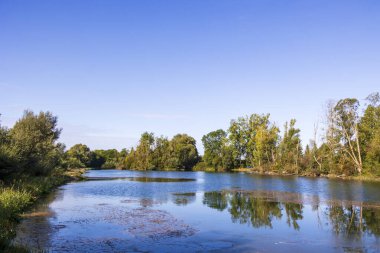 Göl manzarası mavi gökyüzü ve ağaçlarla, Almanya, Mering, 17 Eylül 2025