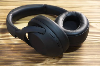 Siyah stereo kulaklıklar ahşap bir arka planda bulunur. Yüksek kalite fotoğraf