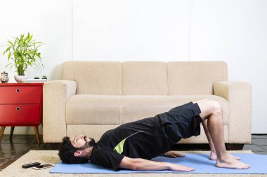 Mavi yogamat köprü poz yapıyor üzerinde siyah giysili güzel beyaz sakallı adam