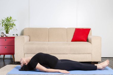 Güzel beyaz esmer kadın mavi yogamat balık yapıyor üzerinde siyah giysiler içinde poz