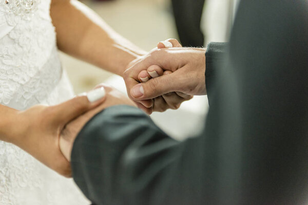 Young married couple holding hands, ceremony wedding day.