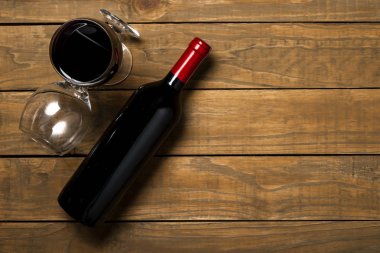 Bir şişe şarap ve ahşap arka plan üzerinde gözlük. Kopya alanı ile üstten görünüm.