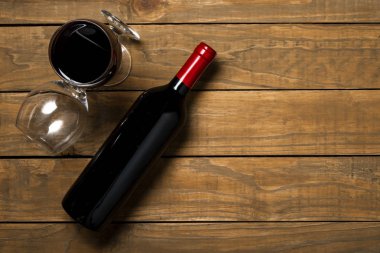 Bir şişe şarap ve ahşap arka plan üzerinde gözlük. Kopya alanı ile üstten görünüm.