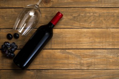 Bir şişe şarap ve cam ve ahşap arka plan üzerinde üzüm. Kopya alanı ile üstten görünüm.
