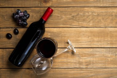 Bir şişe şarap ve gözlük ve üzüm ahşap arka plan üzerinde. Kopya alanı ile üstten görünüm.