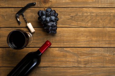Şarap cam şişe açacağı mantarlar ve üzüm ahşap arka plan üzerinde. Kopya alanı ile üstten görünüm.