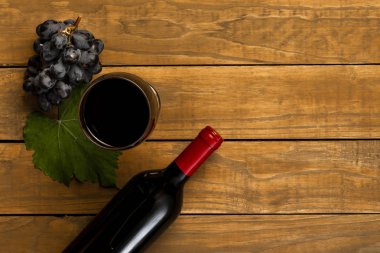 Cam şişe şarap üzüm ve ahşap arka plan asma yaprağı ile. Kopya alanı ile üstten görünüm.