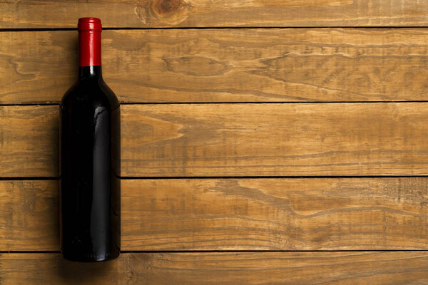 Bottle of wine on wooden background. Top view with copy space.