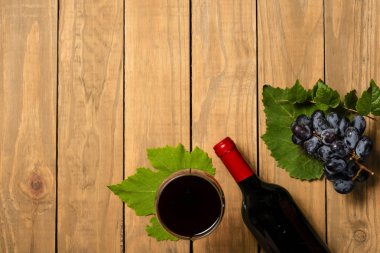 Bir şişe şarap cam ve ahşap arka plan üzerinde üzüm demet. Kopya alanı ile üstten görünüm.