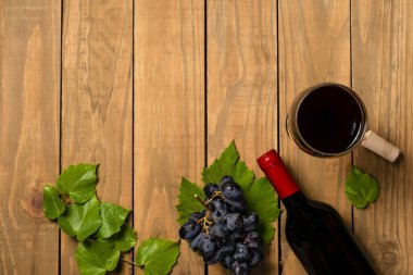 Ahşap arka plan üzerinde üzüm demet şarap cam şişe. Kopya alanı ile üstten görünüm.