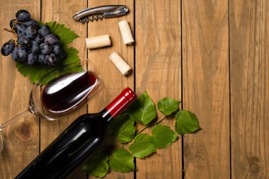 Şişe ve kadeh şarap üzüm demet ve asma kompozisyonu ahşap arka plan üzerinde bırakır. Kopya alanı ile üstten görünüm.