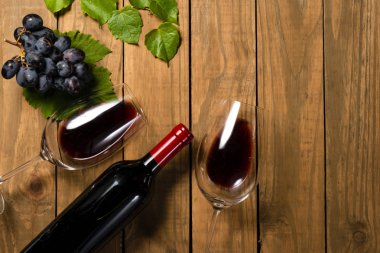 Şişe ve kadeh şarap üzüm demet ve asma kompozisyonu ahşap arka plan üzerinde bırakır. Kopya alanı ile üstten görünüm.