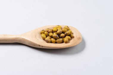 Tahta kaşıkla gri arka plan üzerinde fasulye.