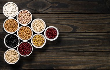 Ürün yelpazesine bir tencerede fasulye. Ahşap siyah arka plan.