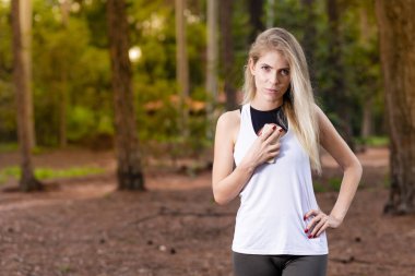 Güzel sarışın genç kadın göğüs - görüntü telefon tutarak günbatımı Park