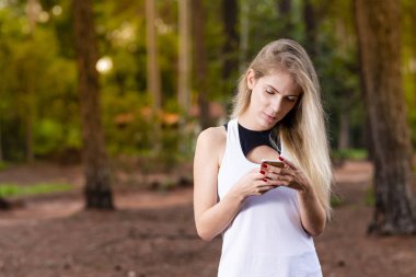 Güzel sarışın genç kadın üstünde hareket eden telefon - görüntü günbatımı gönderen mesaj Park