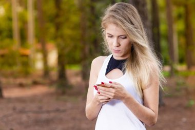 Güzel sarışın genç kadın cep telefonunu - görüntü günbatımı kontrol mesajları Park
