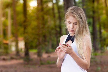 Güzel sarışın genç kadın cep telefonunu - görüntü günbatımı kontrol mesajları Park